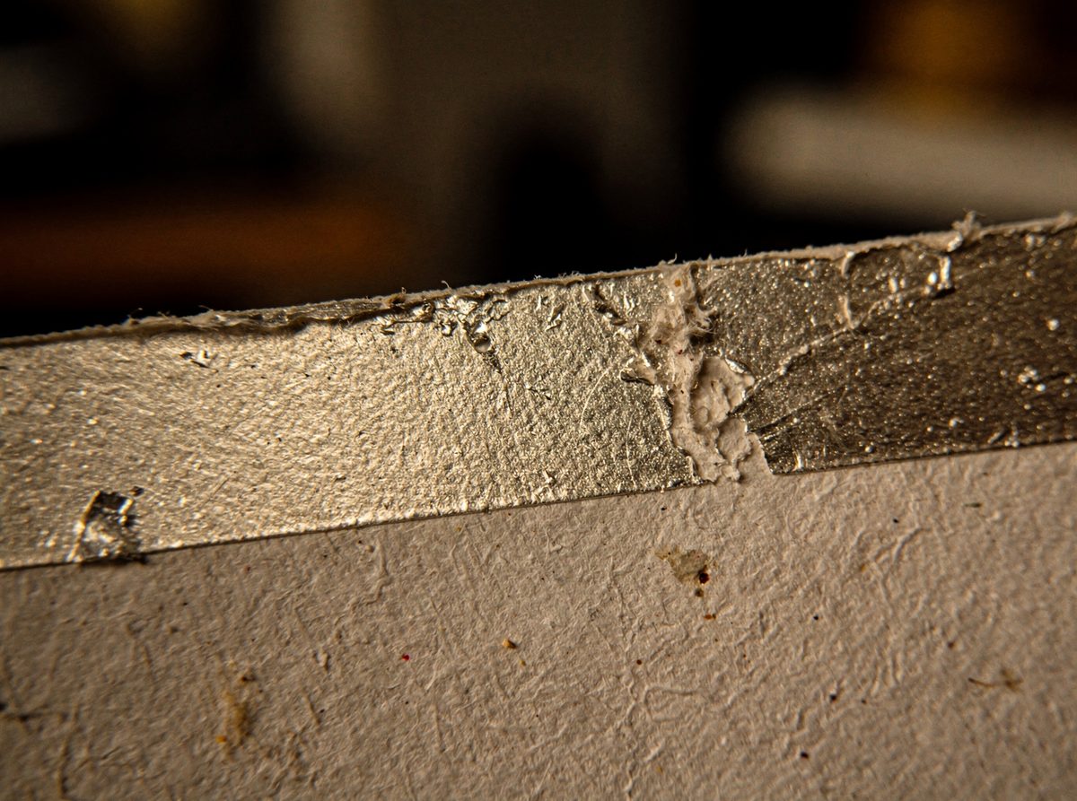 Macro close-up of a foil-stamped label edge catching warm light